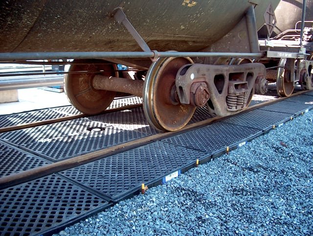 Track pans installed between and beside rails beneath tank cars